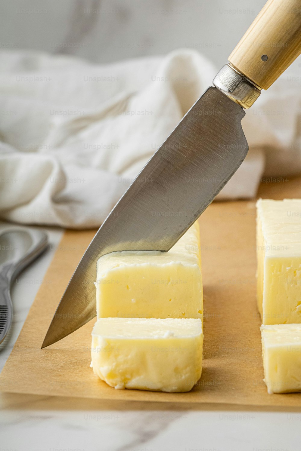 a knife cutting a block of cheese on a cutting board