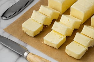 una tabla de cortar con cubos de mantequilla junto a un cuchillo