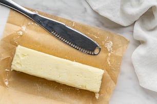 ein Stück Käse auf einem Stück Wachspapier neben einem Messer