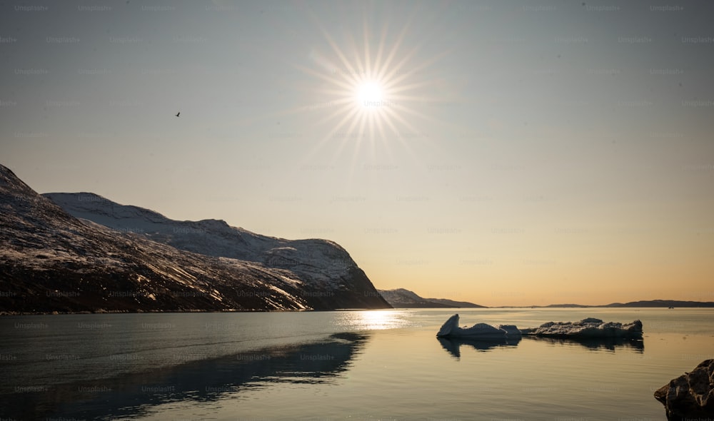 the sun is shining over the mountains and the water