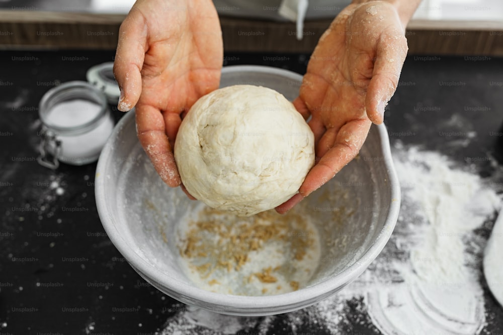 une personne tenant une boule de pâte dans un bol