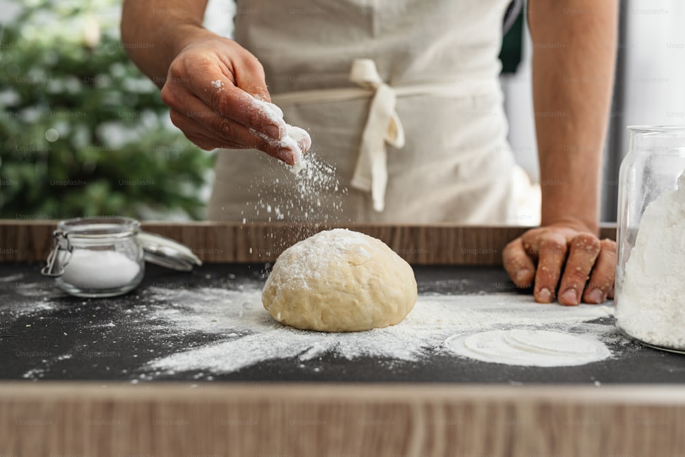 a person sprinkling flour on top of a doughnut