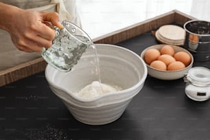 a person pouring water into a bowl of eggs