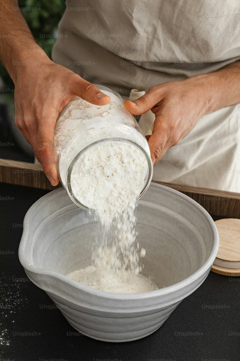 une personne versant de la farine dans un bol sur une table