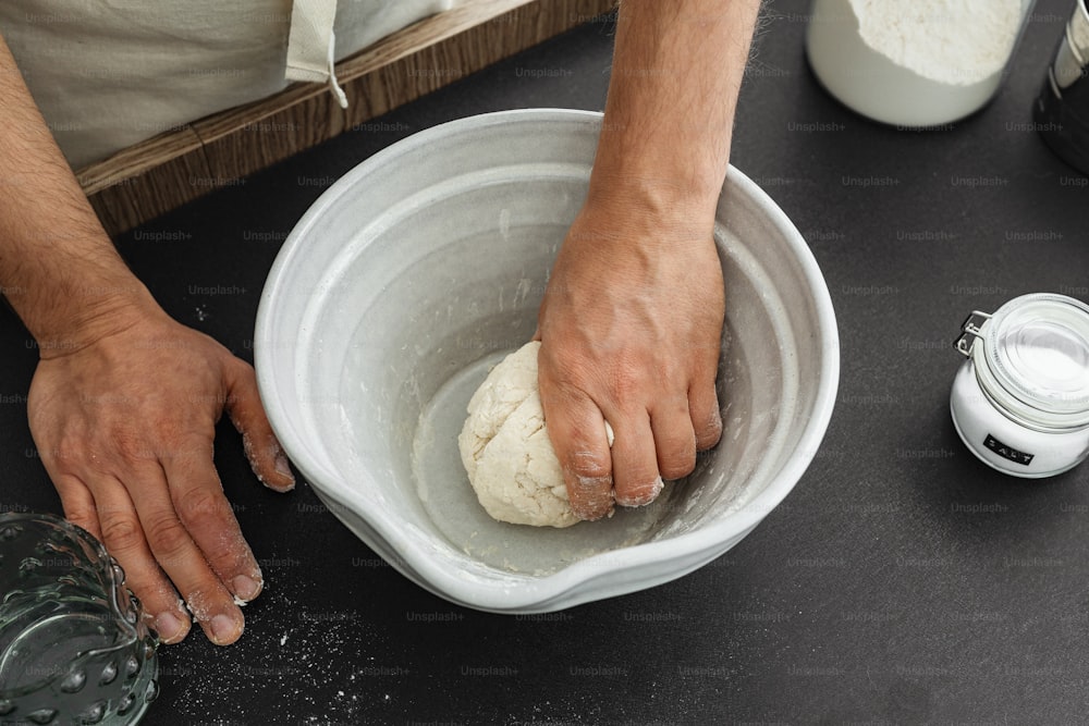 a person holding a ball of dough in a bowl