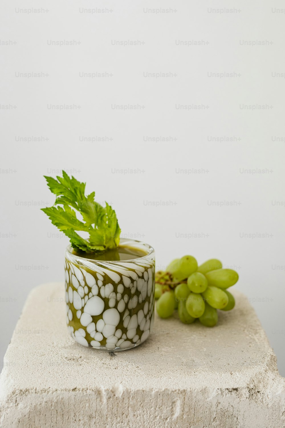 a white and green vase sitting next to a bunch of grapes