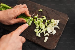 a person cutting up celery on a cutting board