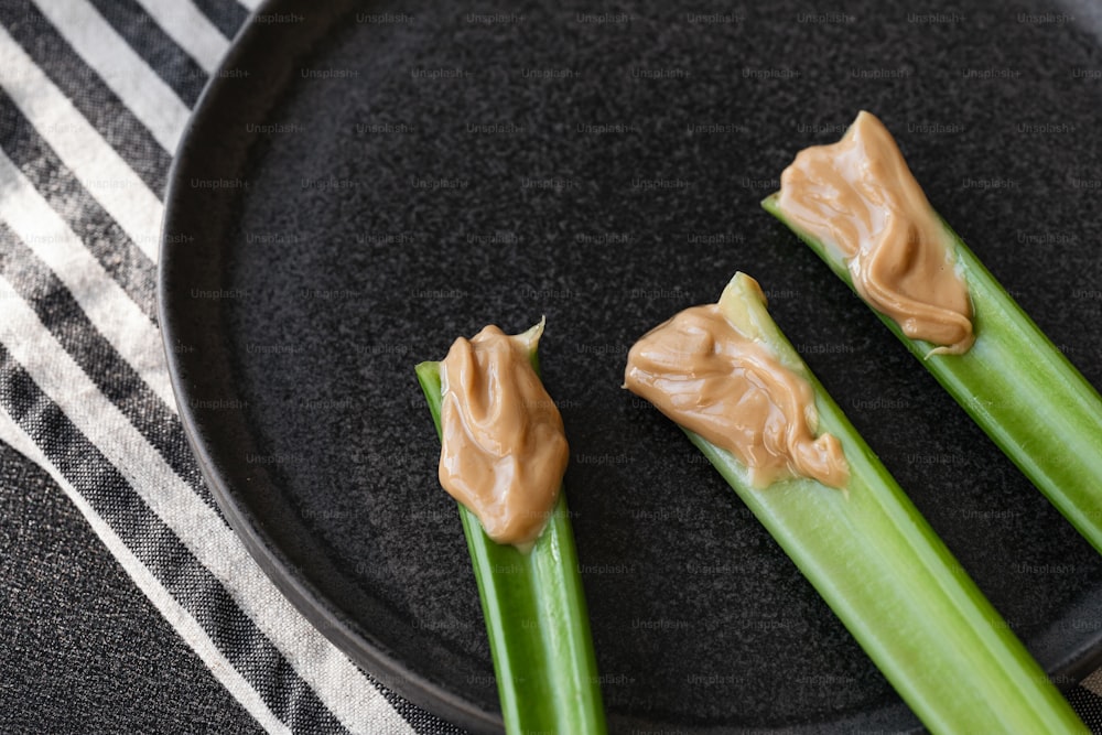 a black plate topped with celery and peanut butter