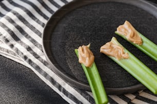 celery sticks with peanut butter on a black plate