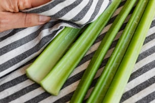 a person cutting celery on a striped cloth