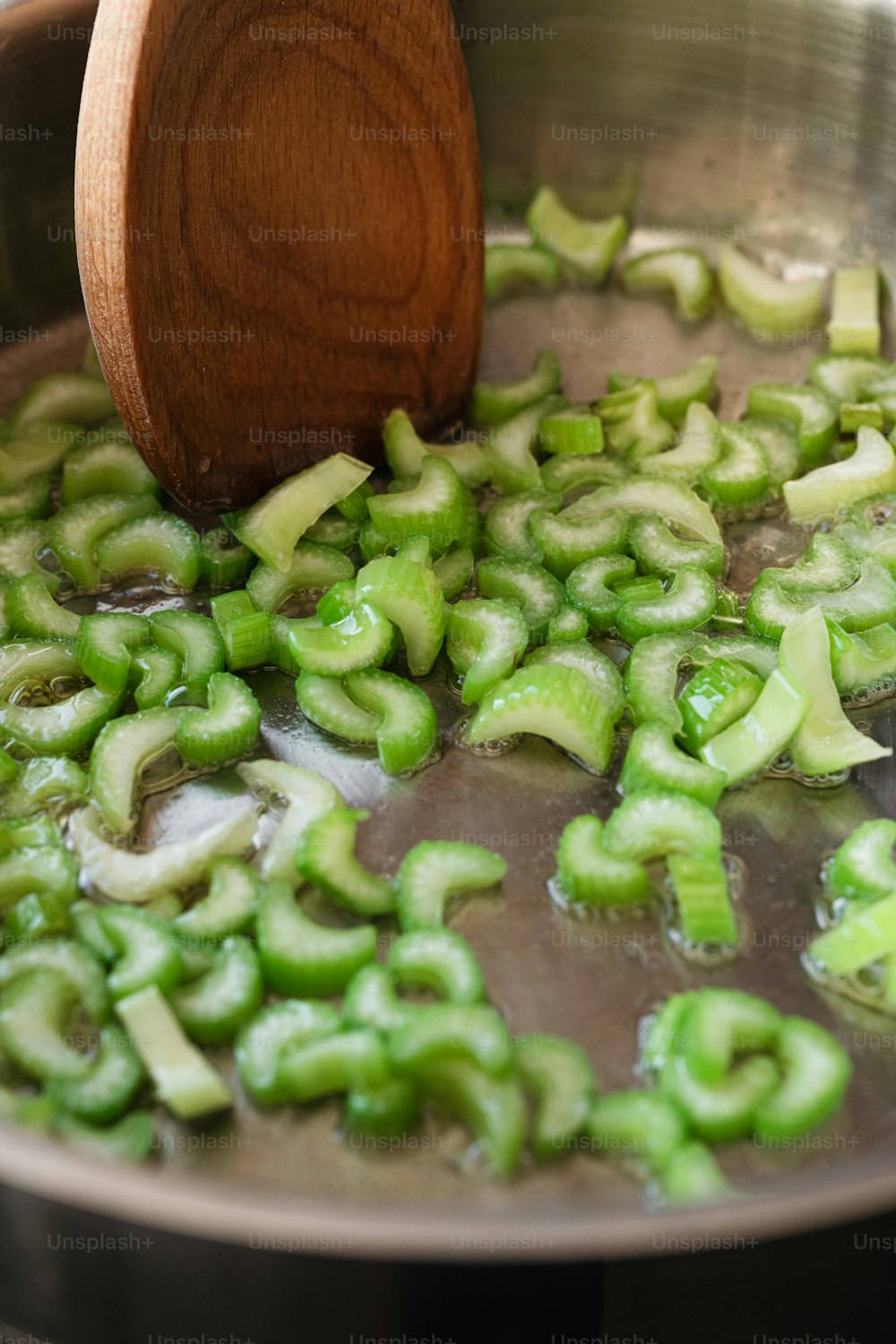 une cuillère en bois remuant une casserole remplie de légumes verts