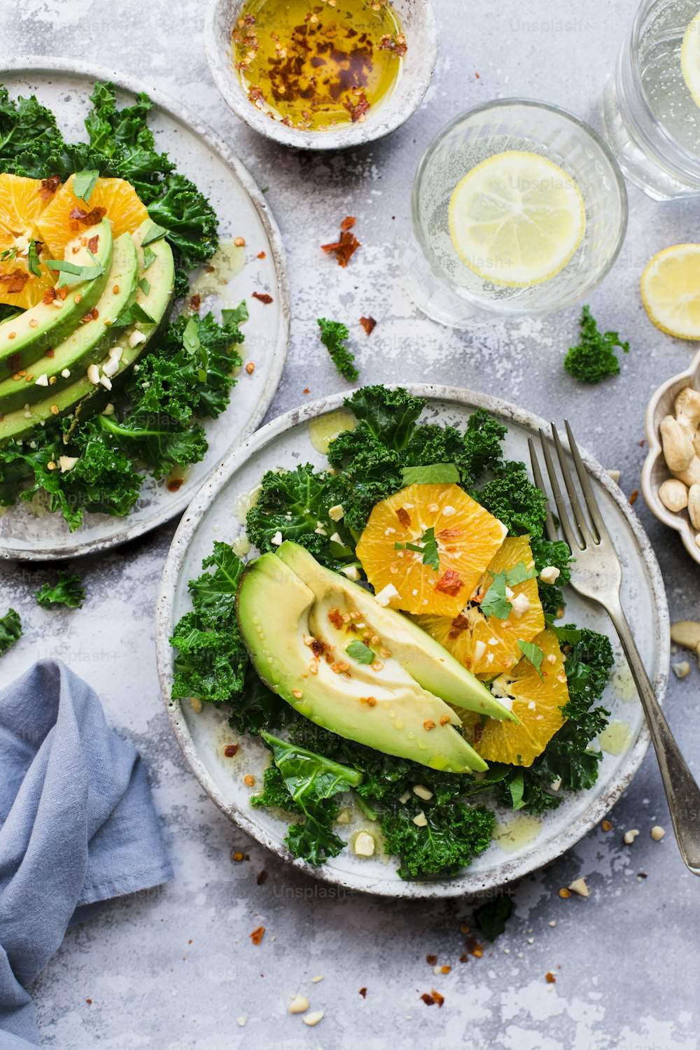two plates of food with avocado, oranges and nuts