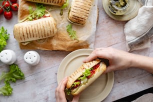 une personne tient un sandwich sur une assiette