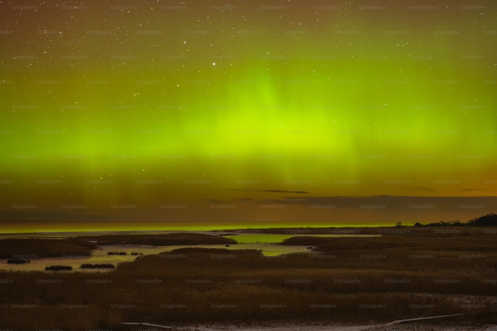a green and yellow aurora over a body of water