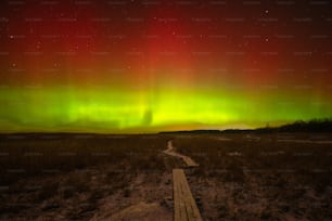 Un sentiero che porta a un'aurora verde e rossa