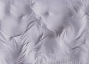 a close up of a bed with a white comforter