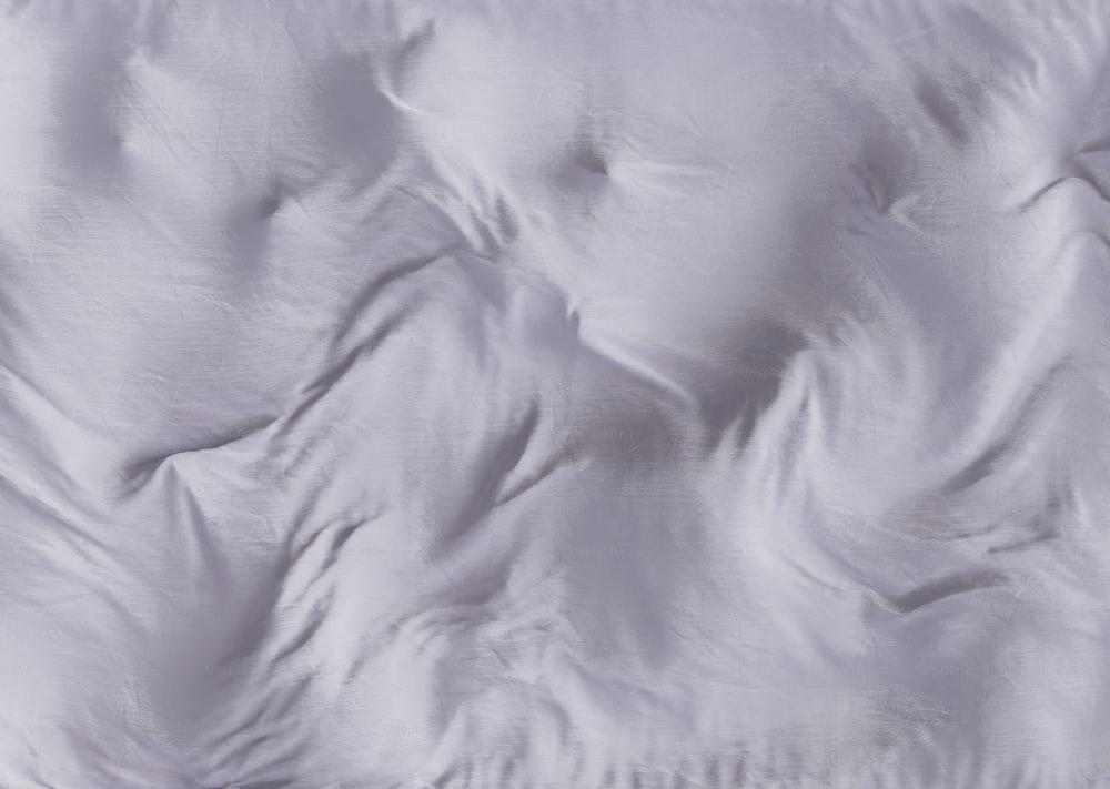Un primer plano de una cama con un edredón blanco