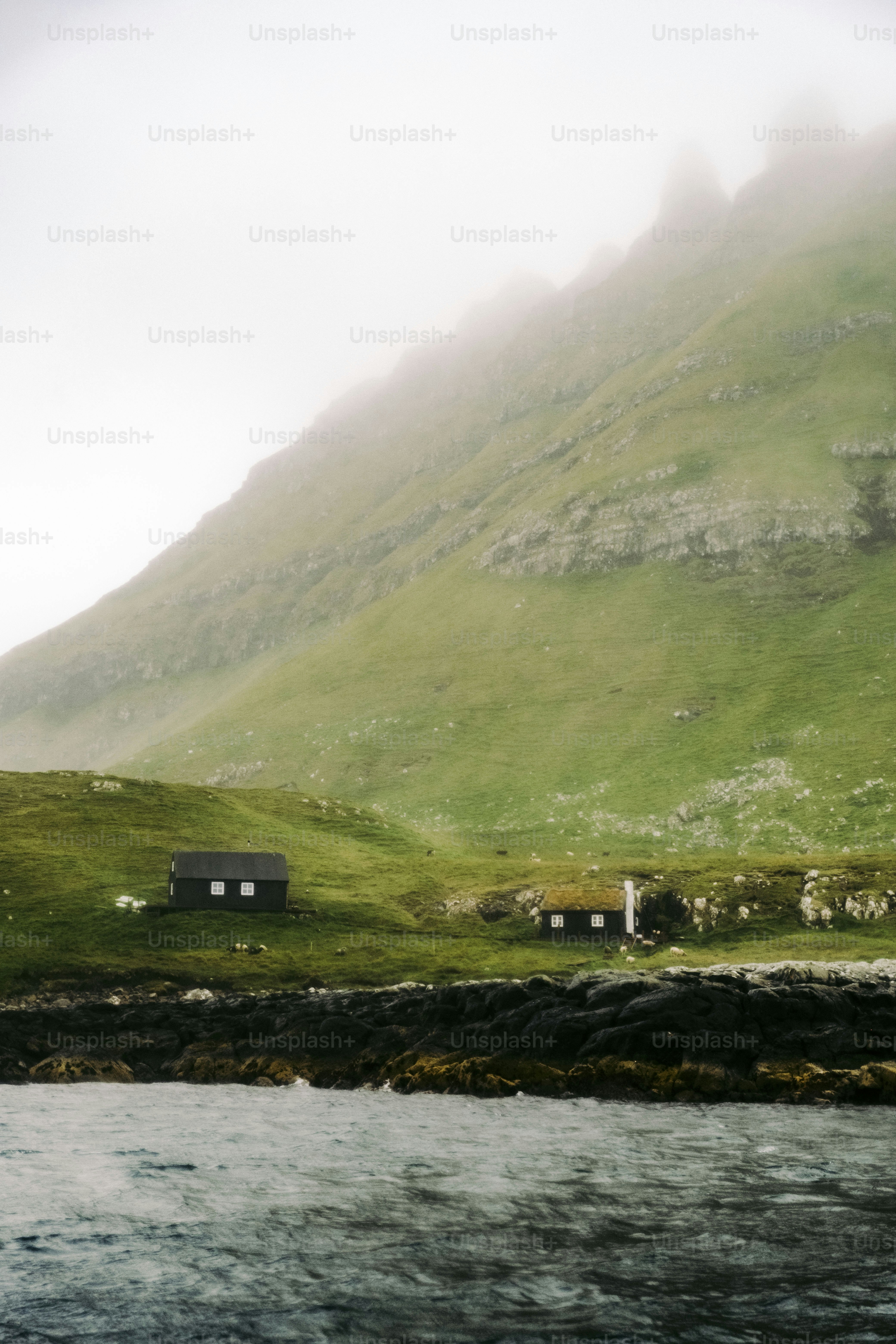 a house on the side of a mountain with a body of water in front of