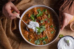 a bowl of chili with sour cream and cilantro