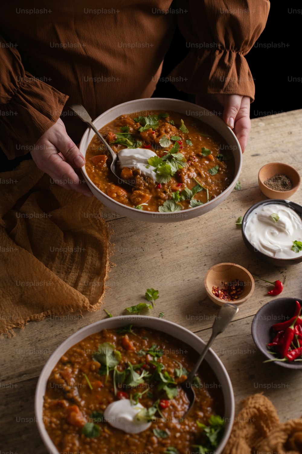 a person holding a bowl of soup on a table