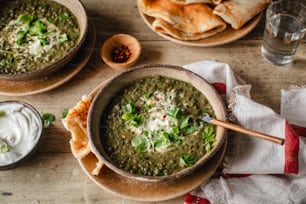 a table topped with bowls of soup and pita bread