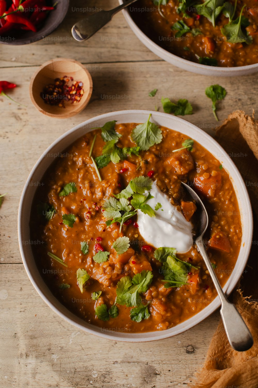 two bowls of chili with sour cream and cilantro