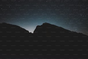 el cielo nocturno con estrellas sobre una cadena montañosa