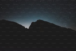 the night sky with stars above a mountain range