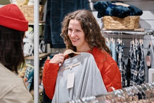 a woman in a red hat is looking at a shirt