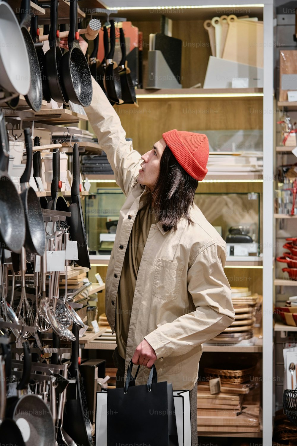 a woman in a red hat is looking at pots and pans