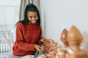 a woman in a red sweater is holding a piece of wood