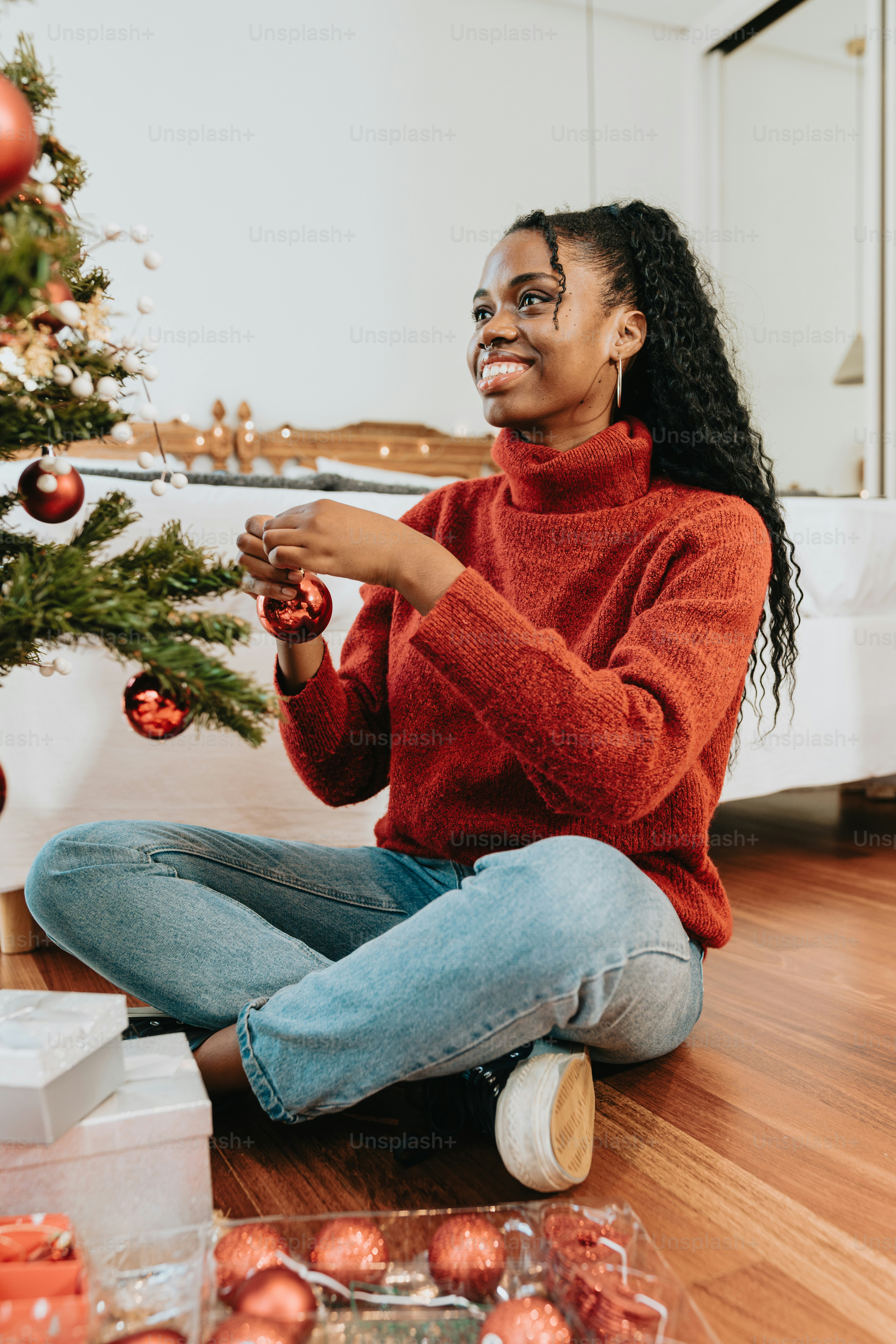 a woman sitting on the floor next to a christmas tree