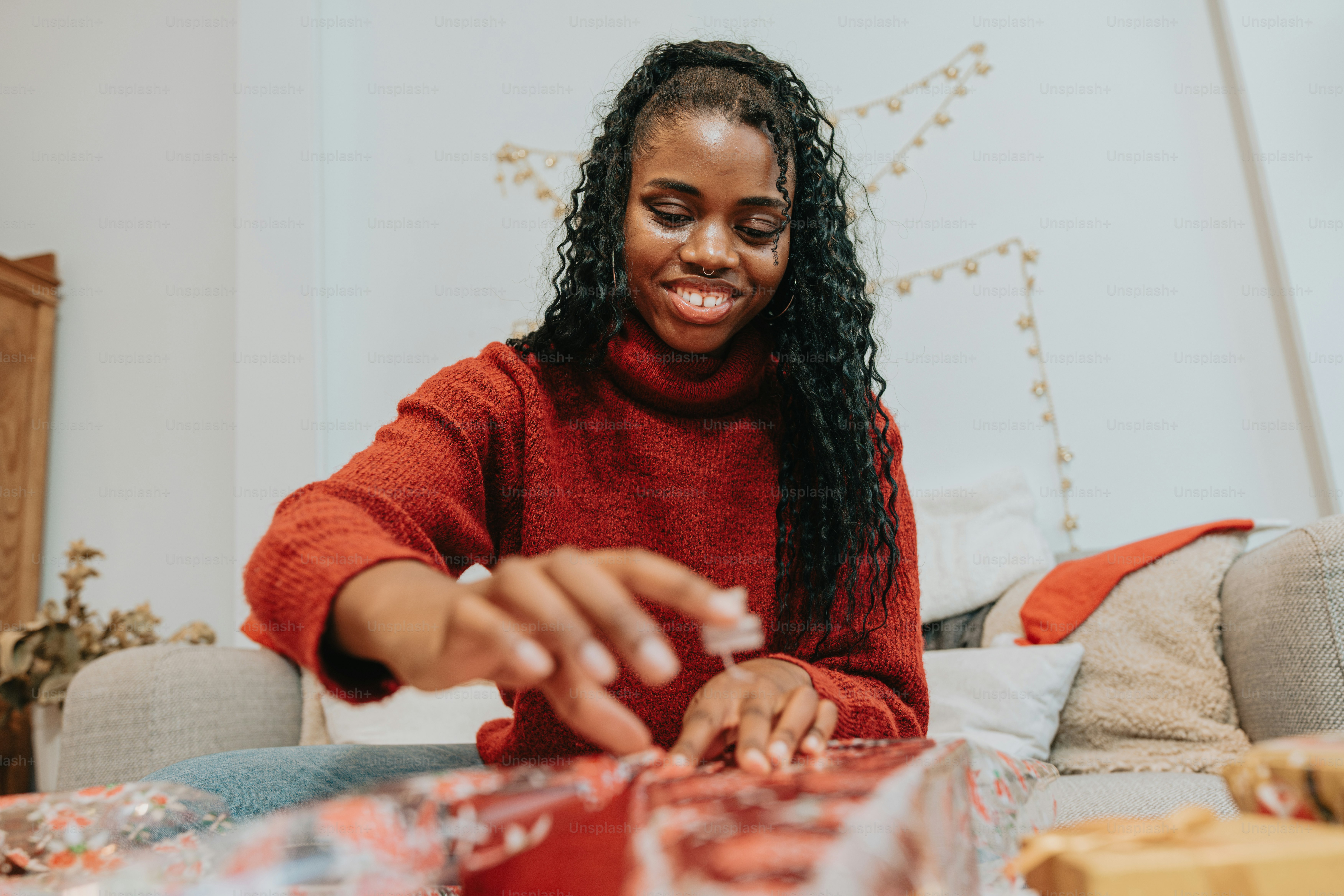 a woman in a red sweater is wrapping presents