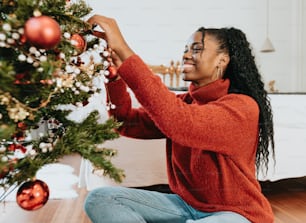 Uma mulher que decora uma árvore de Natal com ornamentos