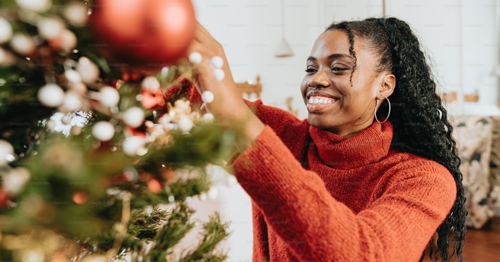 a woman decorating a christmas tree with ornaments