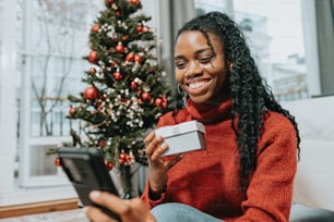 a woman sitting in front of a christmas tree holding a tablet