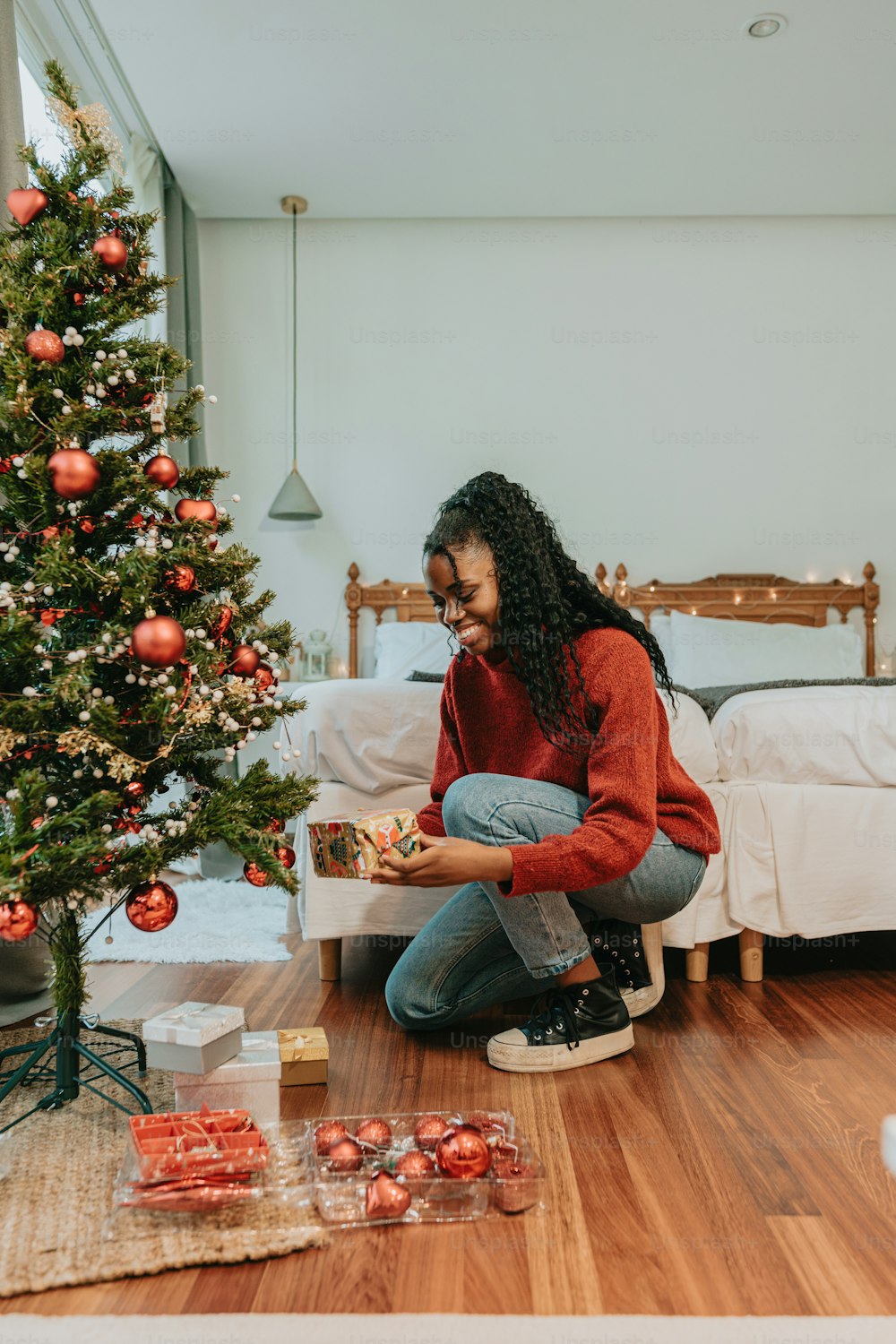 Uma mulher sentada no chão ao lado de uma árvore de Natal