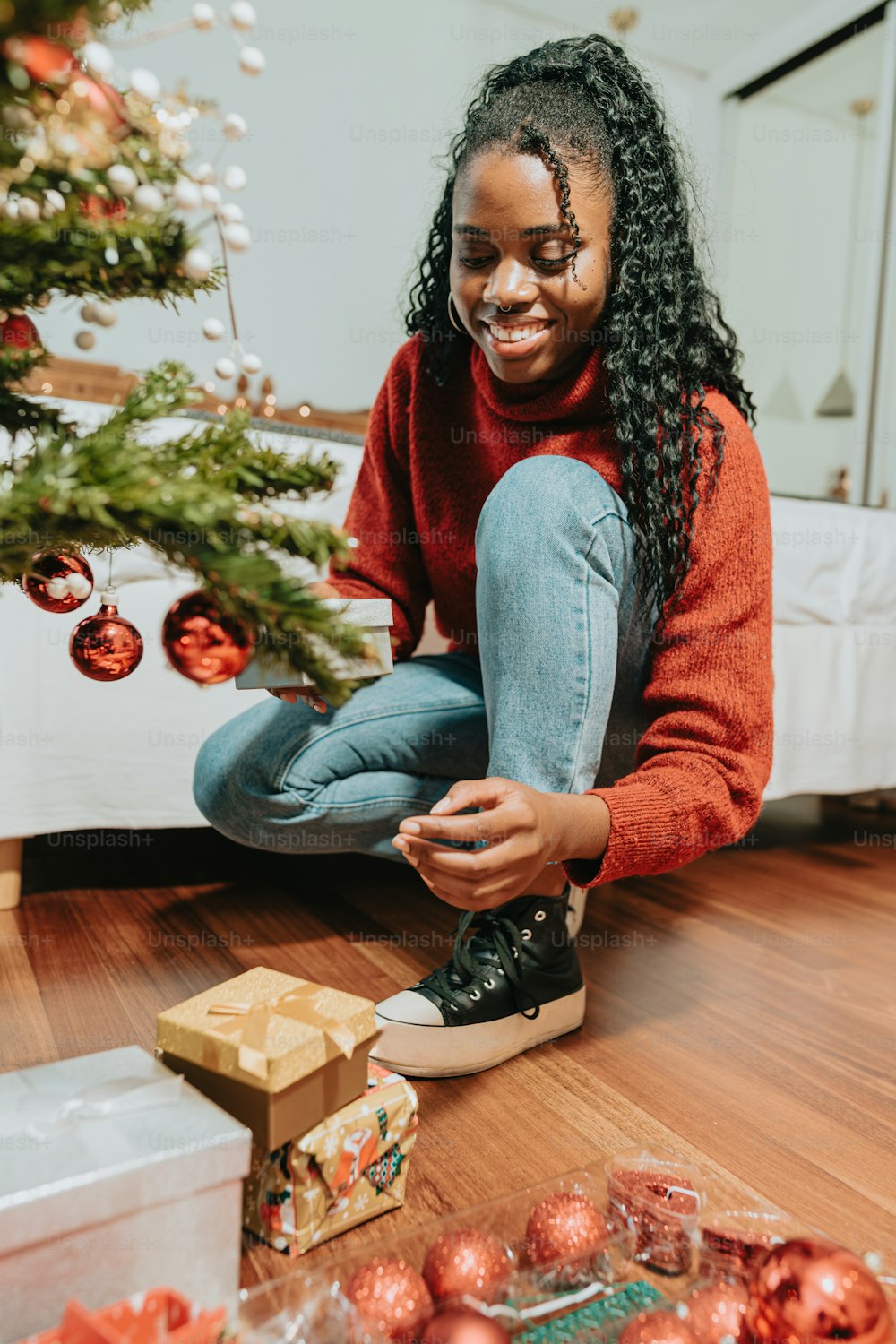 a woman sitting on the floor next to a christmas tree