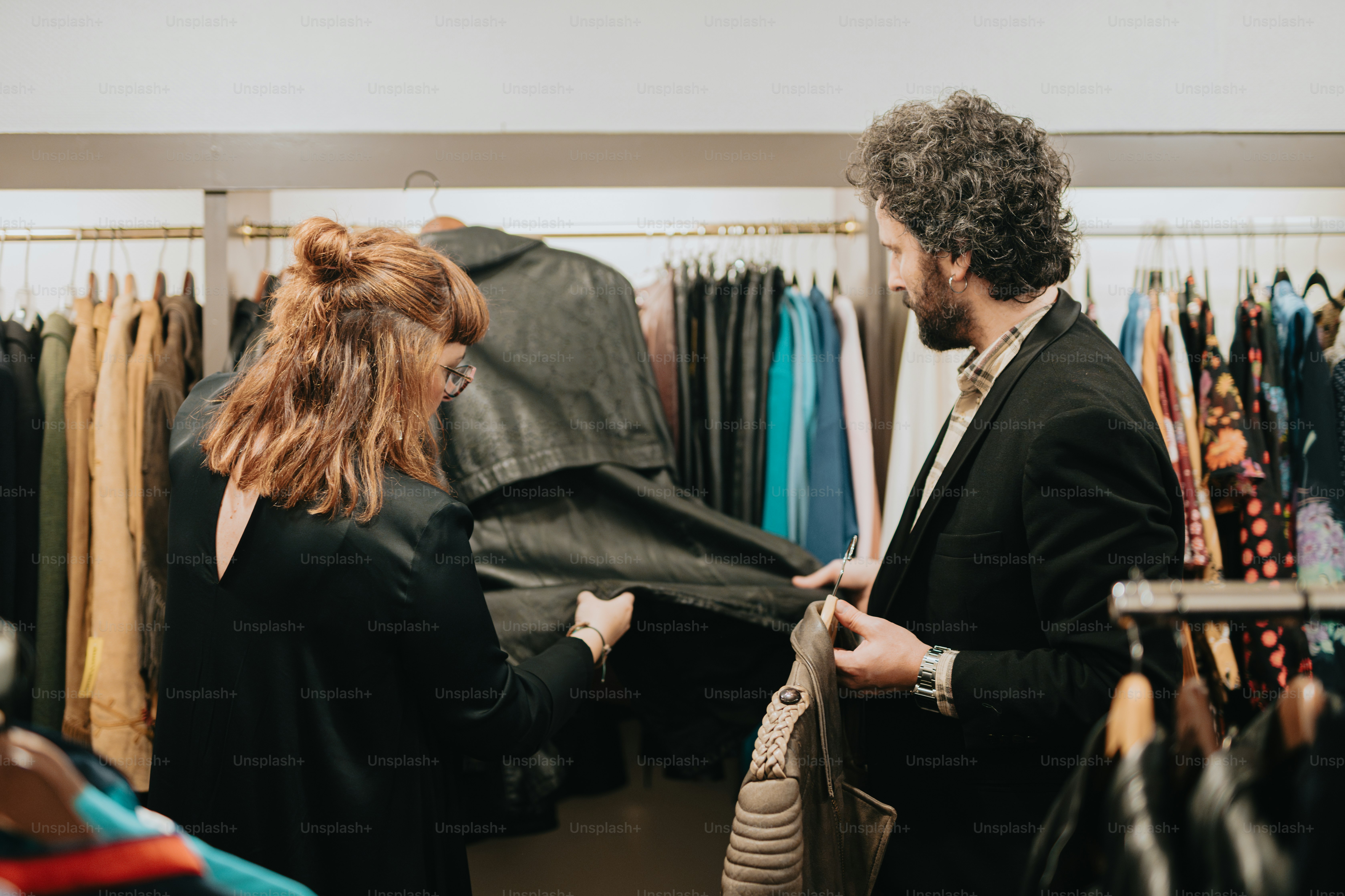 a man and a woman looking at clothes in a store