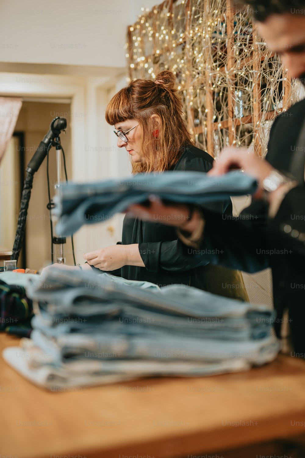 a woman sitting at a table with a pile of clothes