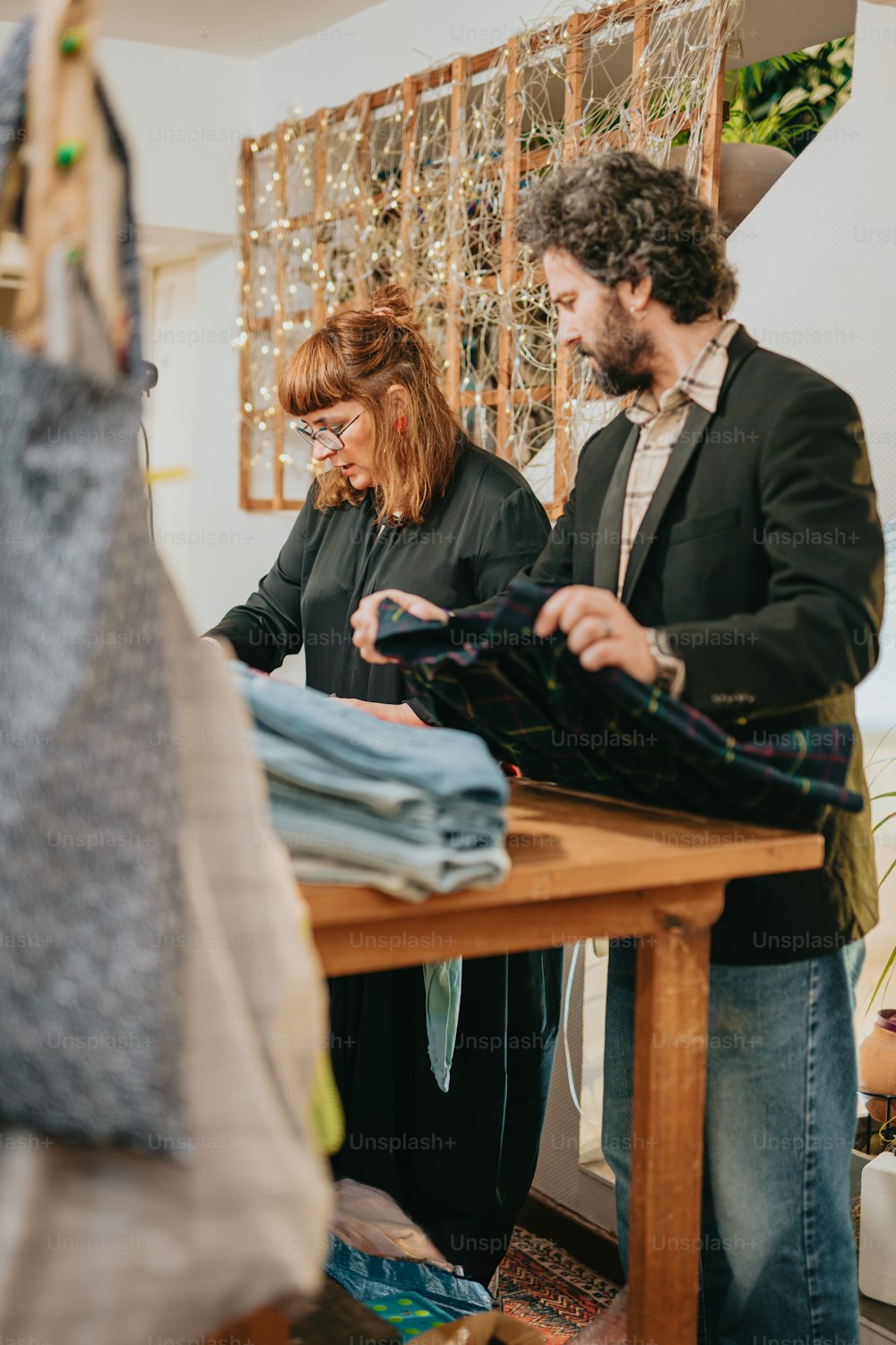 a man and woman looking at clothes on a table