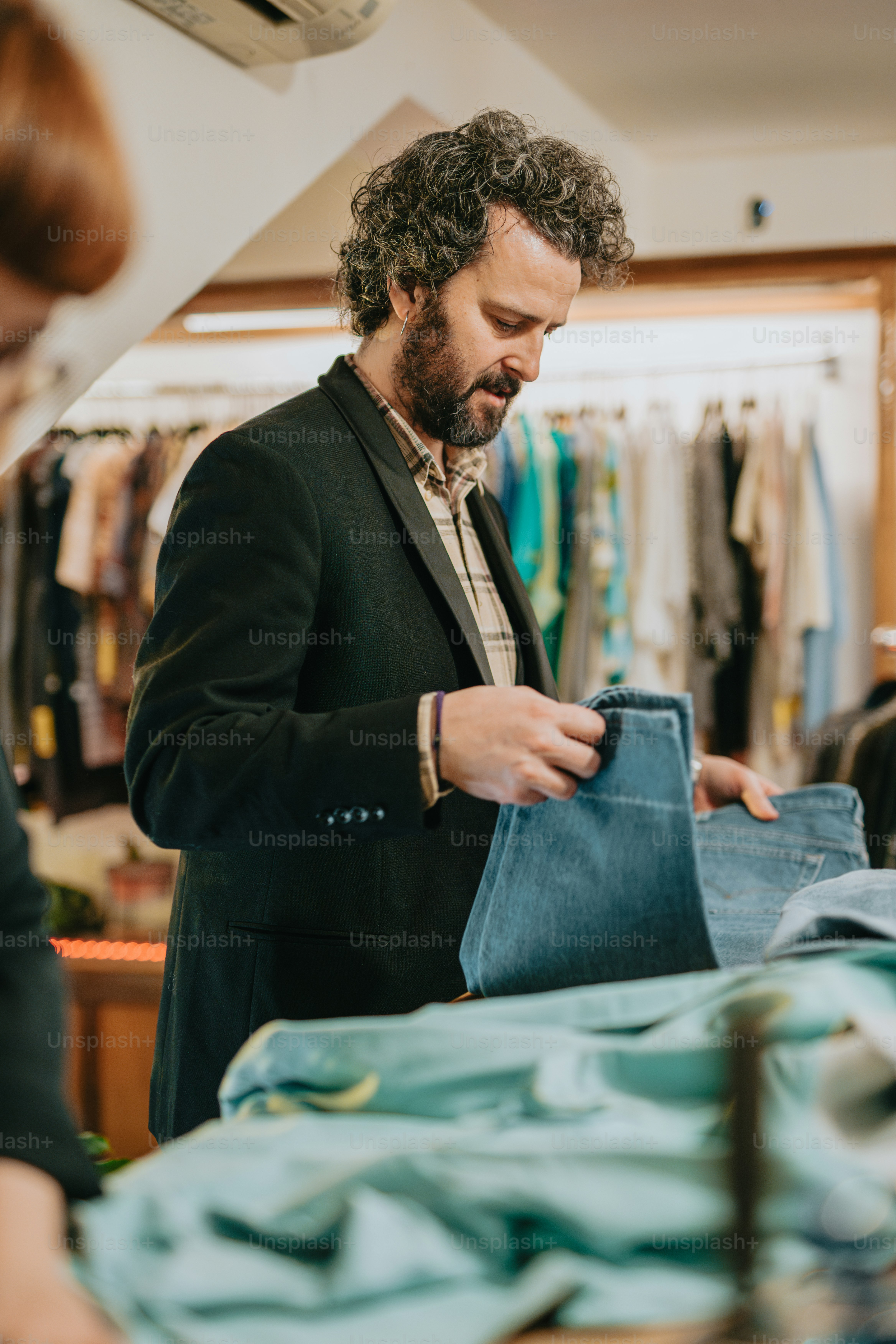 a man in a suit shop looking at a pair of jeans