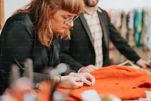 a man and a woman working on a piece of cloth