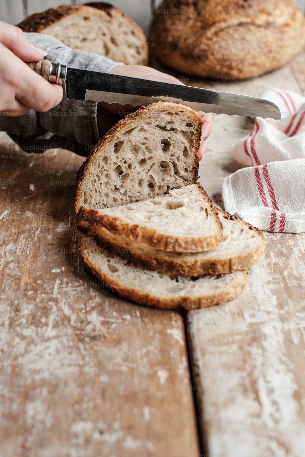 a person cutting a loaf of bread with a knife