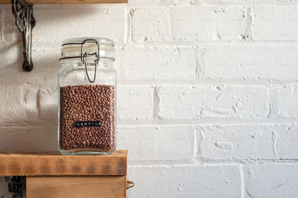 a glass jar filled with coffee beans sitting on top of a wooden shelf