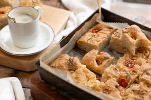 a pan filled with food next to a cup of coffee