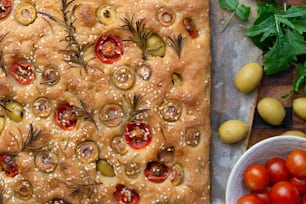 a pizza with olives, tomatoes, and herbs on it