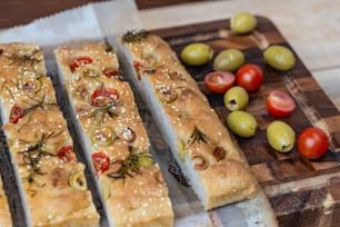 a cutting board with olives, tomatoes, and bread