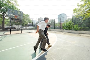 um homem e um menino jogando basquete em uma quadra