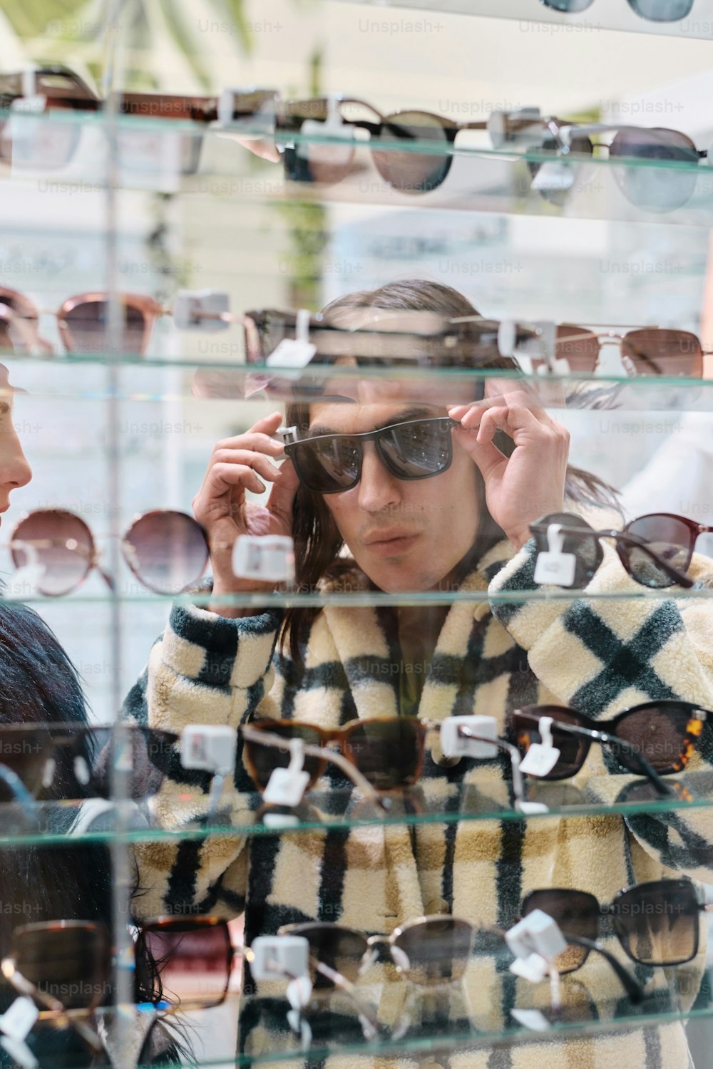 a man and woman looking at sunglasses in a store window